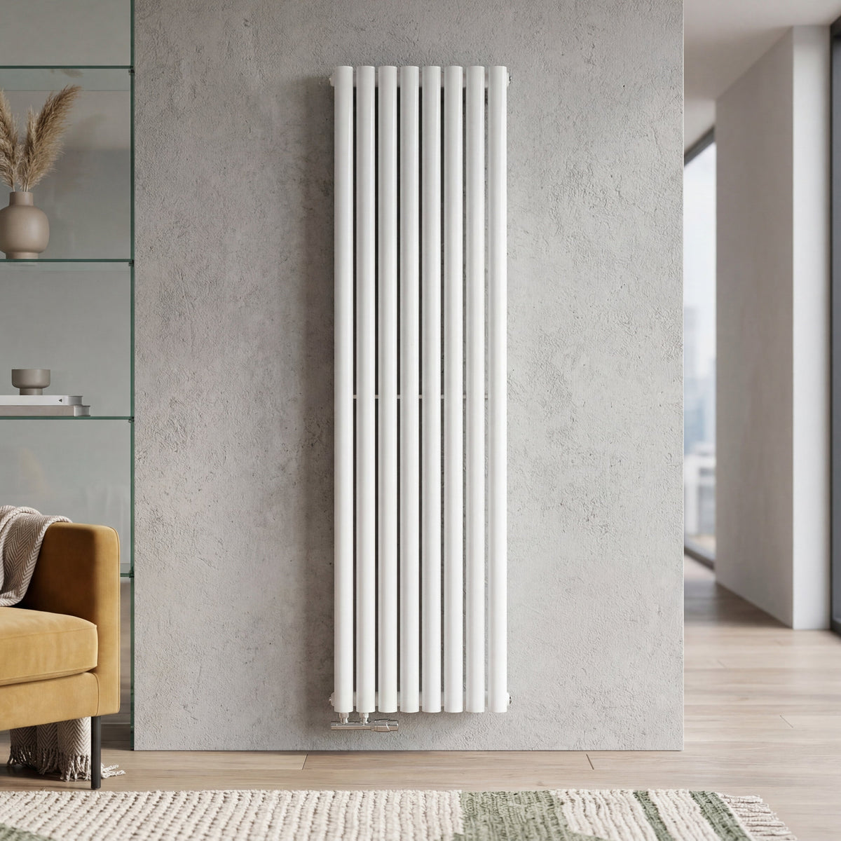 A tall, white vertical panel radiator mounted on a textured gray wall in a modern living room setting with a yellow armchair and large windows.